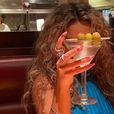 a woman holding a martini glass with olives in it