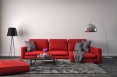 a living room with red couches and pillows on the floor next to a lamp