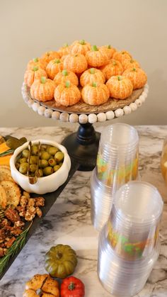 an assortment of food on a table with plates and cups next to it, including pumpkins