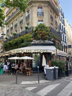 people sitting at tables in front of a cafe