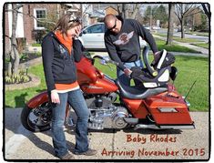 a man and woman standing next to a red motorcycle on the side of the road