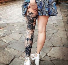 a woman walking down the street with her leg covered in tattoos and holding an umbrella