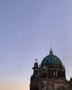 an old building with a dome on top and a moon in the sky above it