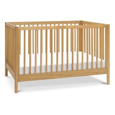 a wooden crib with white sheets on the bottom and side rails, in front of a