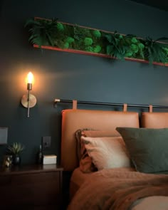 a bed that has some plants on the headboard and lights in the wall above it