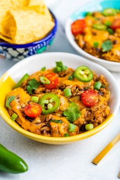 two bowls filled with chili cheese and green peppers