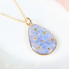 Real pressed forget me not flowers are set in resin in these small teardrop necklaces. Handmade, each pendant is filled with forget-me-not dried flowers that are individually picked, pressed, selected, and placed, creating a beautiful and unique stained glass effect. These necklaces are available with 14k gold plated chain, 14k gold filled chain, or in a silver style with non-tarnishing and hypoallergenic chain. Perfect for nature lovers, as a Mother's day gift, for loss, for long distance relat Blue Teardrop Jewelry With Pressed Flowers, Blue Teardrop Pressed Flower Jewelry, Necklaces Handmade, Titanium Earrings, Forget Me Nots, Botanical Jewelry, Jewelry Blue, Teardrop Necklace, Teardrop Pendant