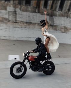 a man riding on the back of a motorcycle next to a woman in a white dress