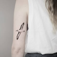 a woman's arm with a bird tattoo on the left side of her arm