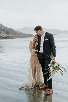 a bride and groom standing on the beach