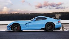 a blue sports car is parked near the water