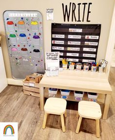 a child's desk with two stools in front of it and a bulletin board on the wall