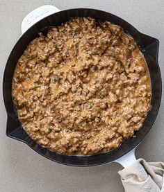 a skillet filled with food sitting on top of a counter next to a cloth