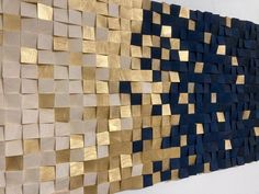 a wall sculpture made out of wood and gold foiled metal strips on the side