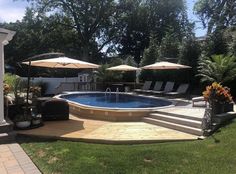 an above ground pool surrounded by lawn chairs and umbrellas in a backyard with decking