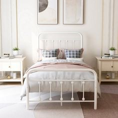 a white bed sitting in a bedroom next to two pictures on the wall above it