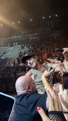 a man with his hand up in the air at a concert, surrounded by people