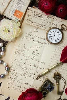 an old fashioned pocket watch sitting on top of a piece of paper next to roses