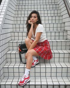 a woman sitting on some stairs with her hand under her chin