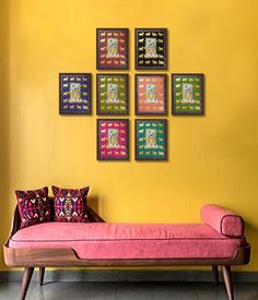 a pink couch sitting in front of a yellow wall with nine framed pictures on it