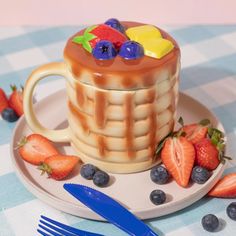 a waffle cake on a plate with strawberries and blueberries next to it