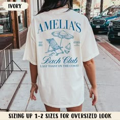 the back of a woman's shirt that says, stella's beach club sitting up to 2 sizes for oversized look