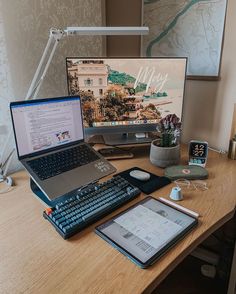 a laptop computer sitting on top of a wooden desk next to a monitor and keyboard