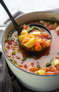 a ladle full of stew with vegetables being spooned into the pot and ready to be eaten