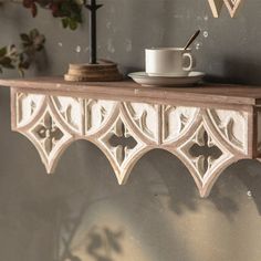 a cup and saucer on a shelf in the corner of a room with flowers