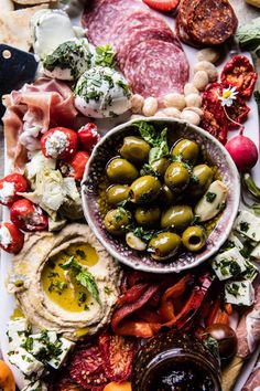 a platter filled with olives, meat and vegetables