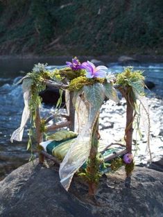 a chair decorated with flowers sitting on top of a rock next to a body of water