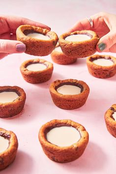 a person reaching for some kind of dessert in front of other small ones on a pink surface