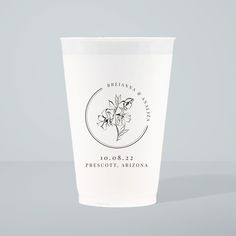 a white cup with a flower on the front and logo on the side, sitting on a table