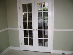 two white double doors in the corner of a room with gray walls and tile flooring