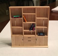 a wooden book shelf with drawers and books on it, sitting on top of a table