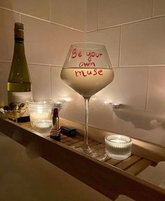 a wine glass sitting on top of a wooden shelf next to a bottle and glasses