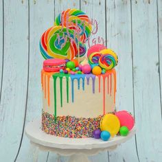 a multicolored birthday cake with sprinkles and balloons on the top