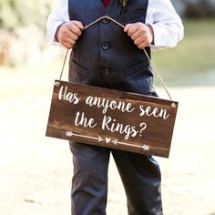 a little boy in a suit holding a sign that says has anyone seen the kings?