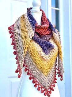 a crocheted shawl is displayed on a mannequin