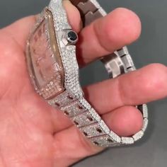 a person holding a watch in their hand with diamond bracelets on it's wrist