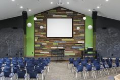 an empty classroom with blue chairs and a projector screen in the middle of the room