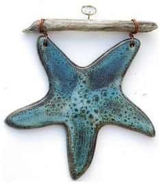 a blue starfish hanging on a wooden branch with a hook in the shape of a fish