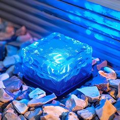 an ice cube sitting on top of some rocks next to a blue window sill