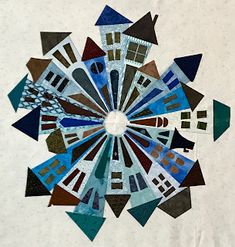 a circular piece of art made out of different colored squares and shapes on white paper