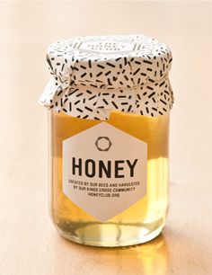 a jar filled with honey sitting on top of a wooden table next to a tag