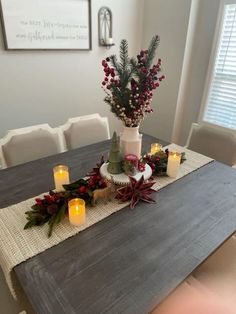 a dining room table with candles and flowers on the centerpiece, surrounded by greenery