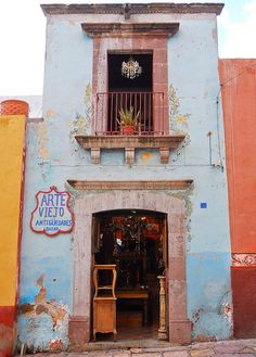 an old building with a sign that says arte viejo and chairs are in the doorway