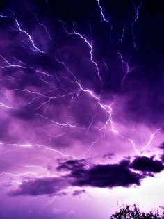 the sky is filled with lightning and purple hues, as seen from an airplane