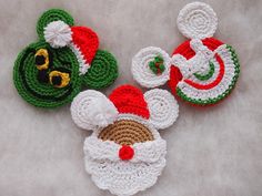 three crocheted christmas ornaments are laying on a white surface, one is green and the other is red