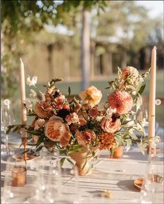 a vase filled with flowers sitting on top of a table next to candles and wine glasses